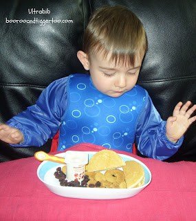 A little boy sitting at a table with a plate of food, with Product