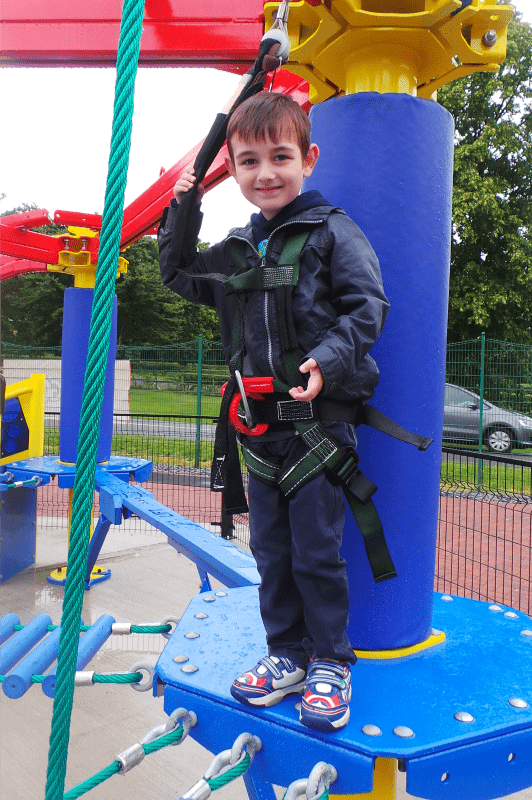 A little boy standing in front of a playground