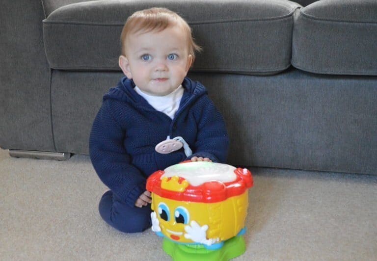 A little boy sitting in a chair holding a baby