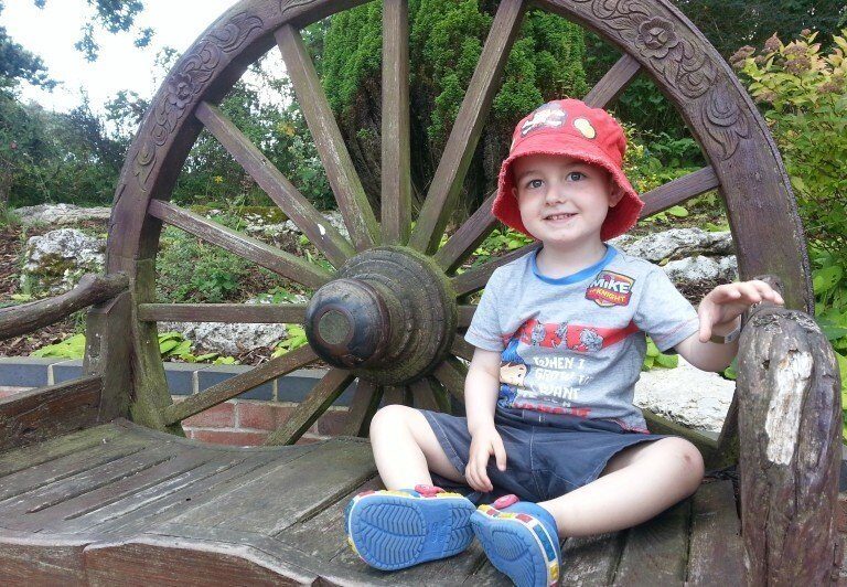 A little boy sitting on a wooden bench
