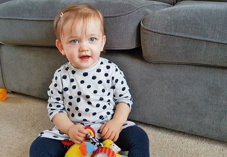 A small child sitting on a couch holding a baby