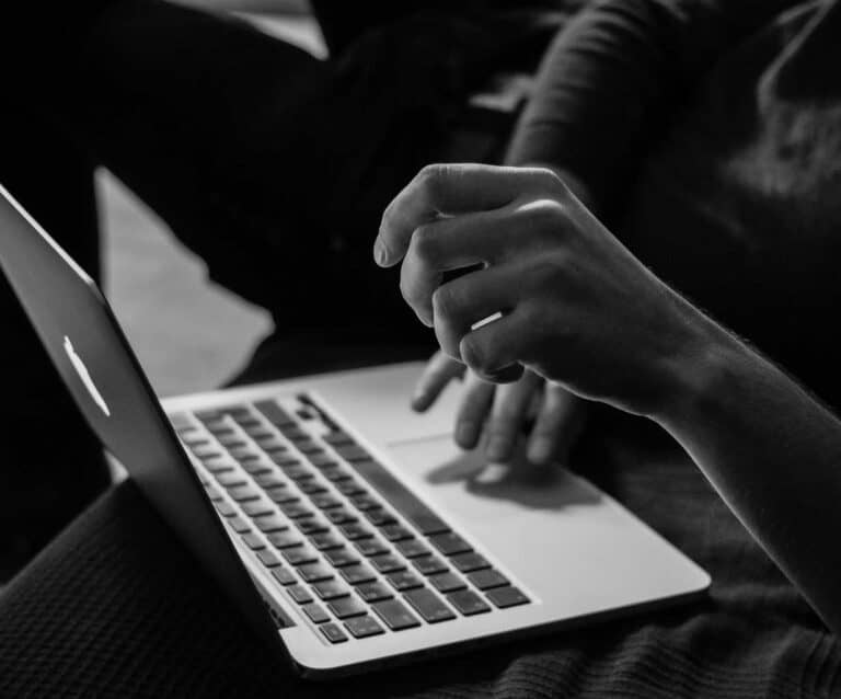 A person using a laptop computer sitting on top of a table