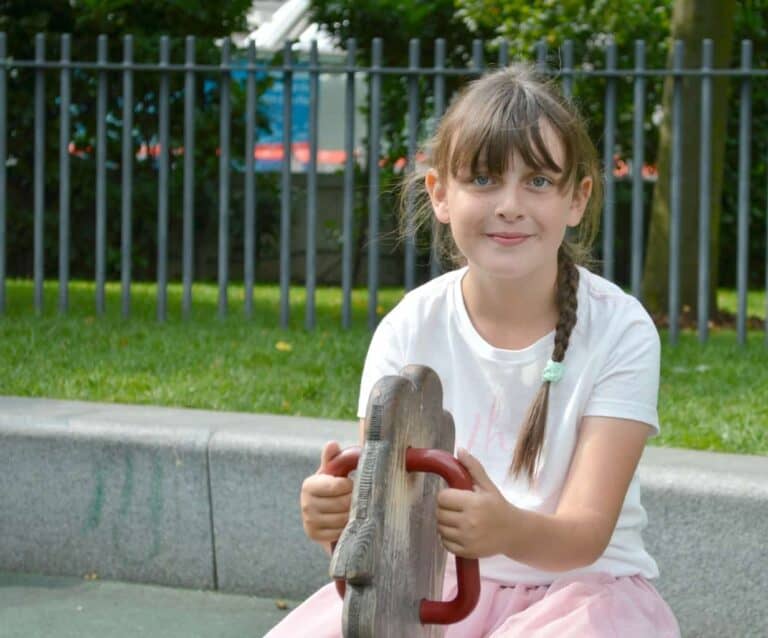 A little girl sitting at a zoo