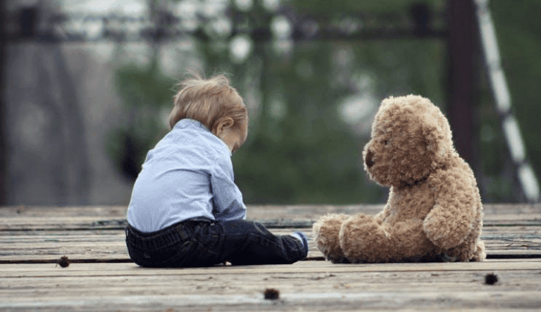 A teddy bear sitting on top of a wooden fence