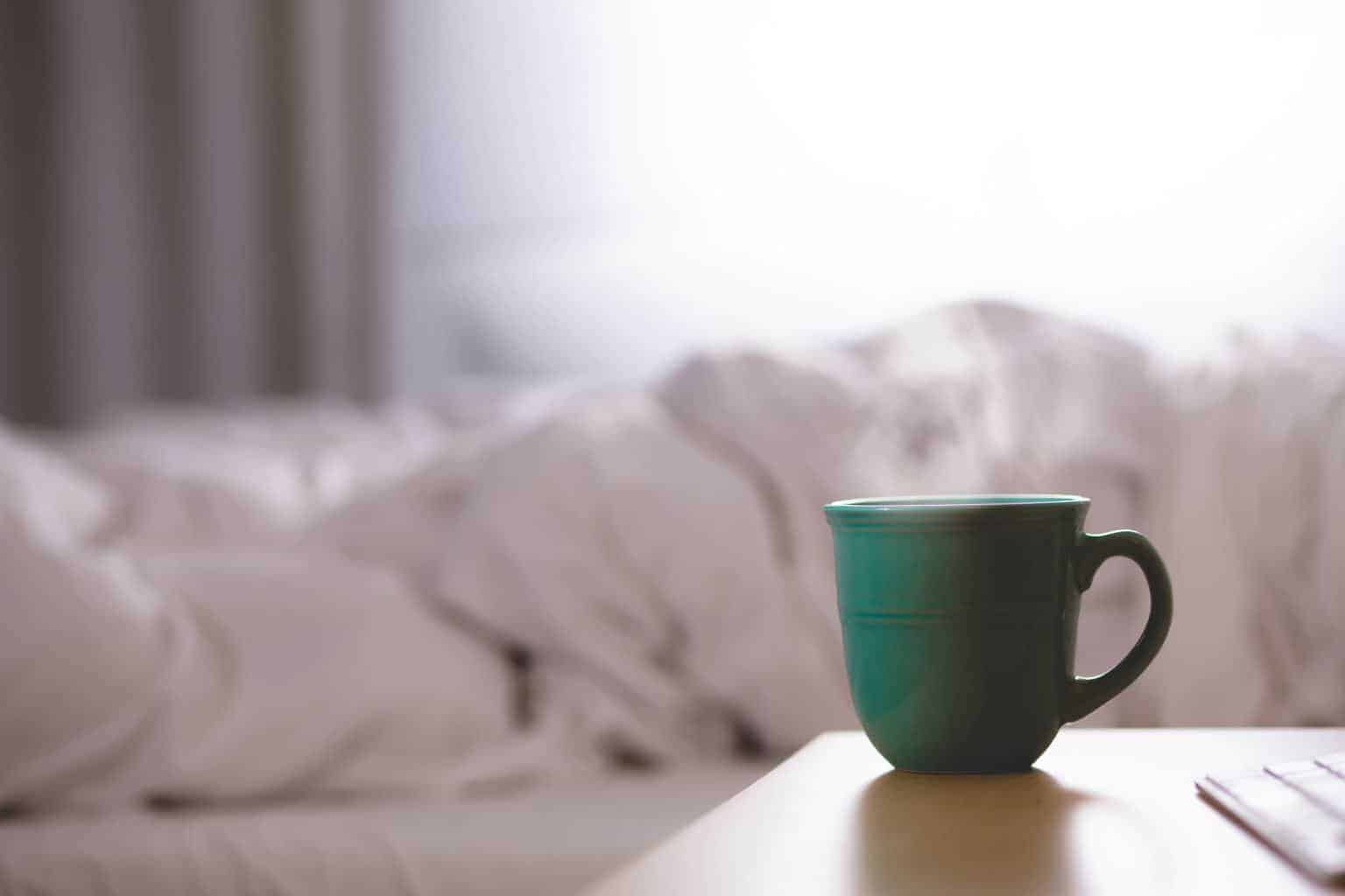 A cup of coffee sitting on top of a bed