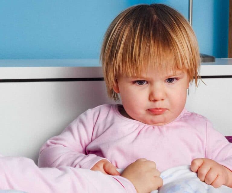 A baby sitting on a bed