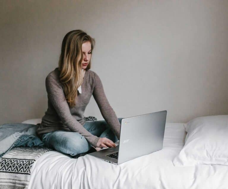 A person sitting on a bed using a laptop