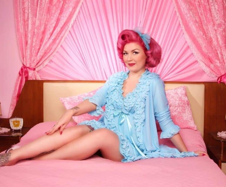 A girl in a pink dress sitting on a bed