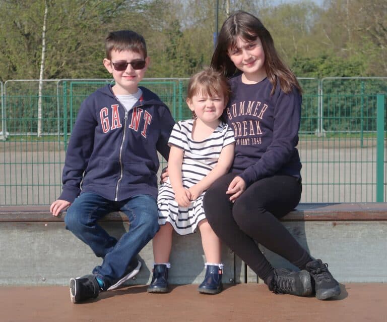A couple of people that are sitting on the side of a fence