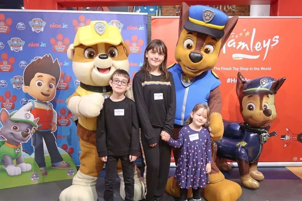 A group of people standing next to a stuffed toy posing for the camera