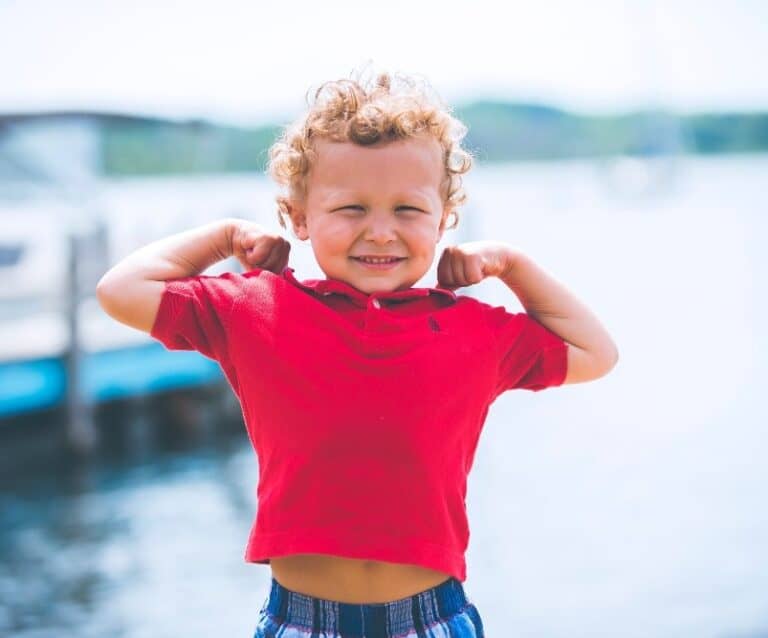 A little girl standing next to a body of water