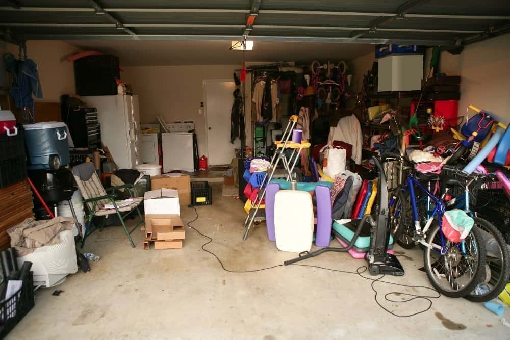 Tips To Declutter Your Garage - A pile of luggage sitting on top of clothes in a room