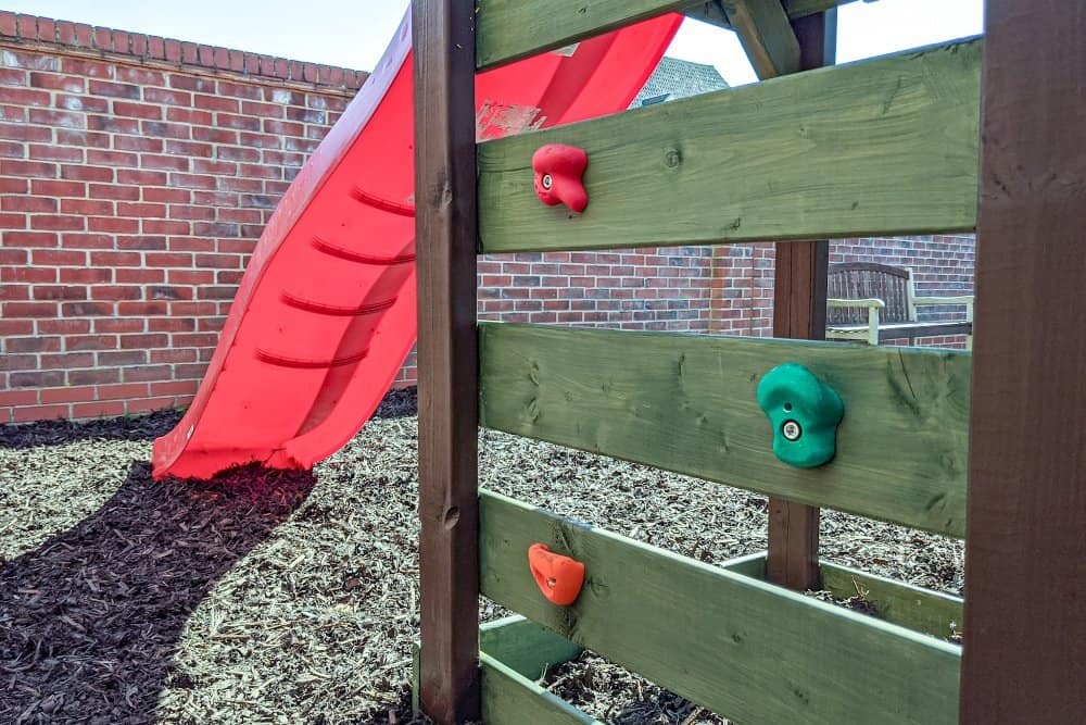 A close up of a wooden climbing frame rock wall