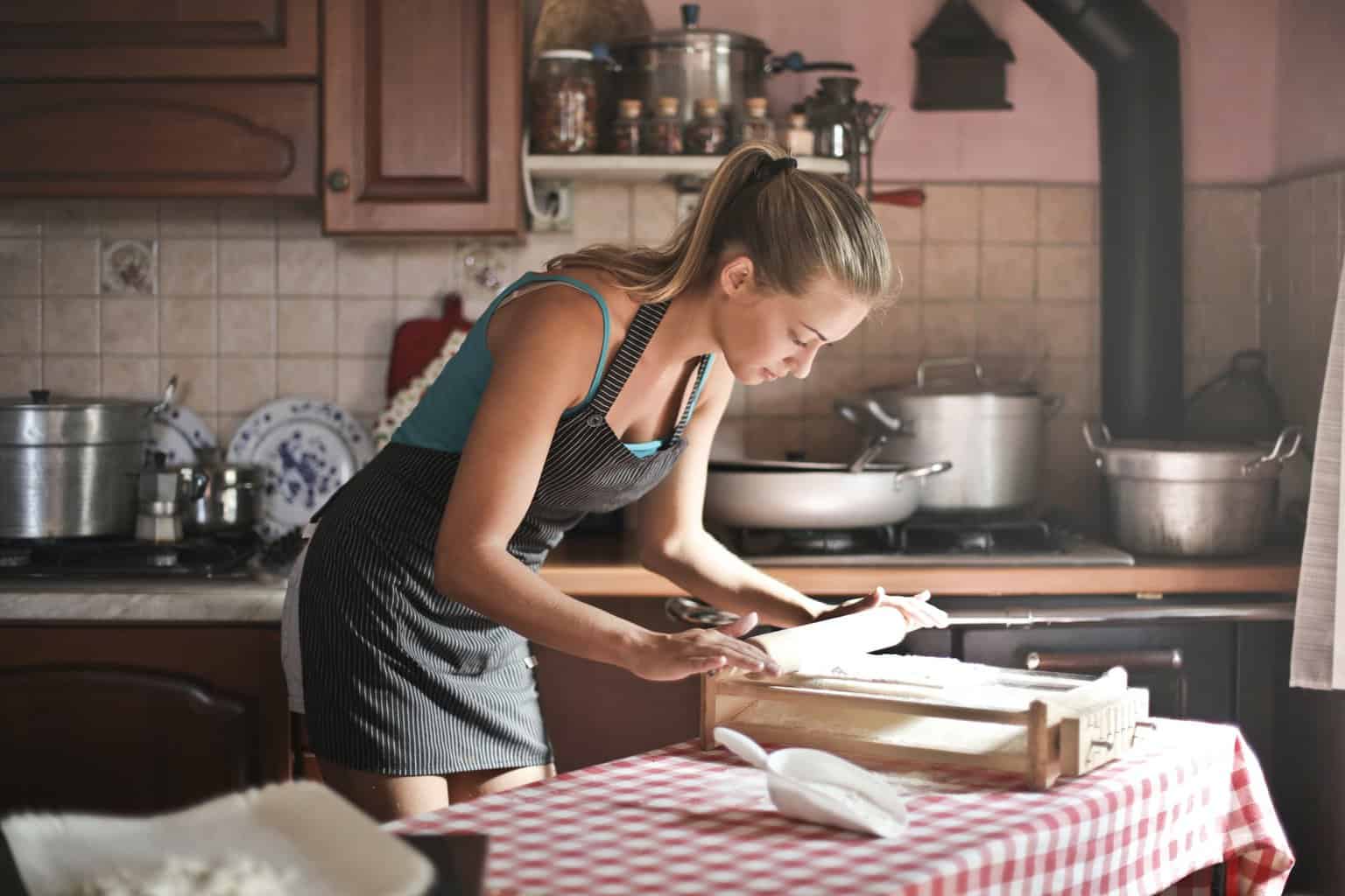 Why You Should Learn to Cook Like a Pro - young woman rolling dough for baking in kitchen