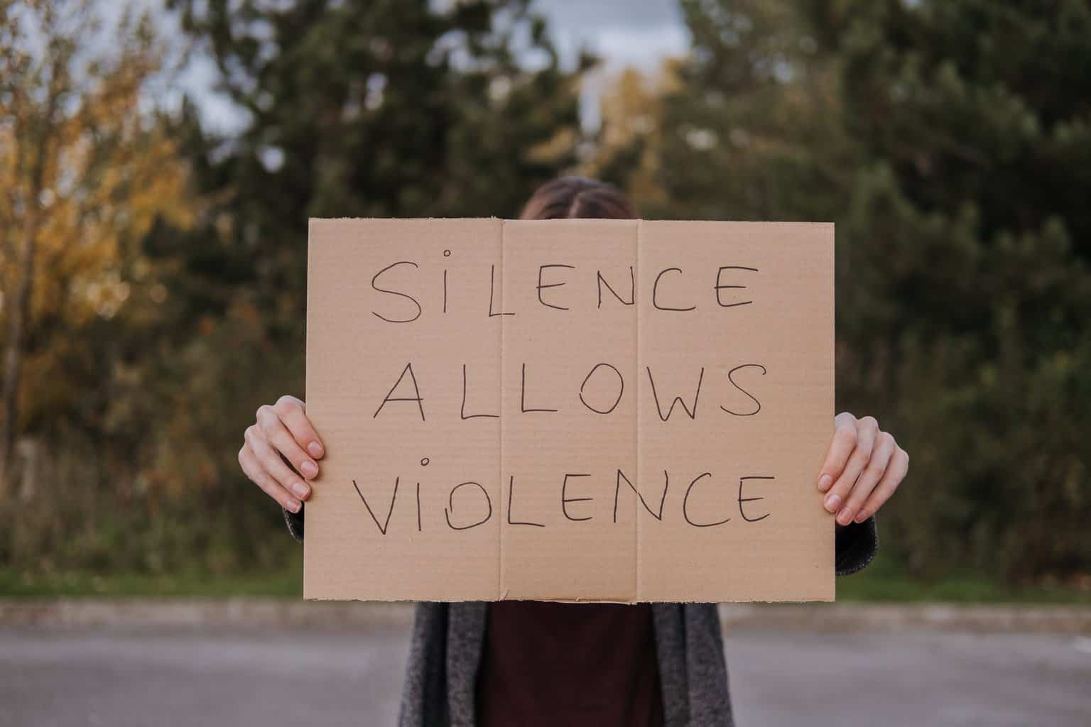 6 Domestic Violence Facts - a person demonstrating carton with slogan 
silence allows violence