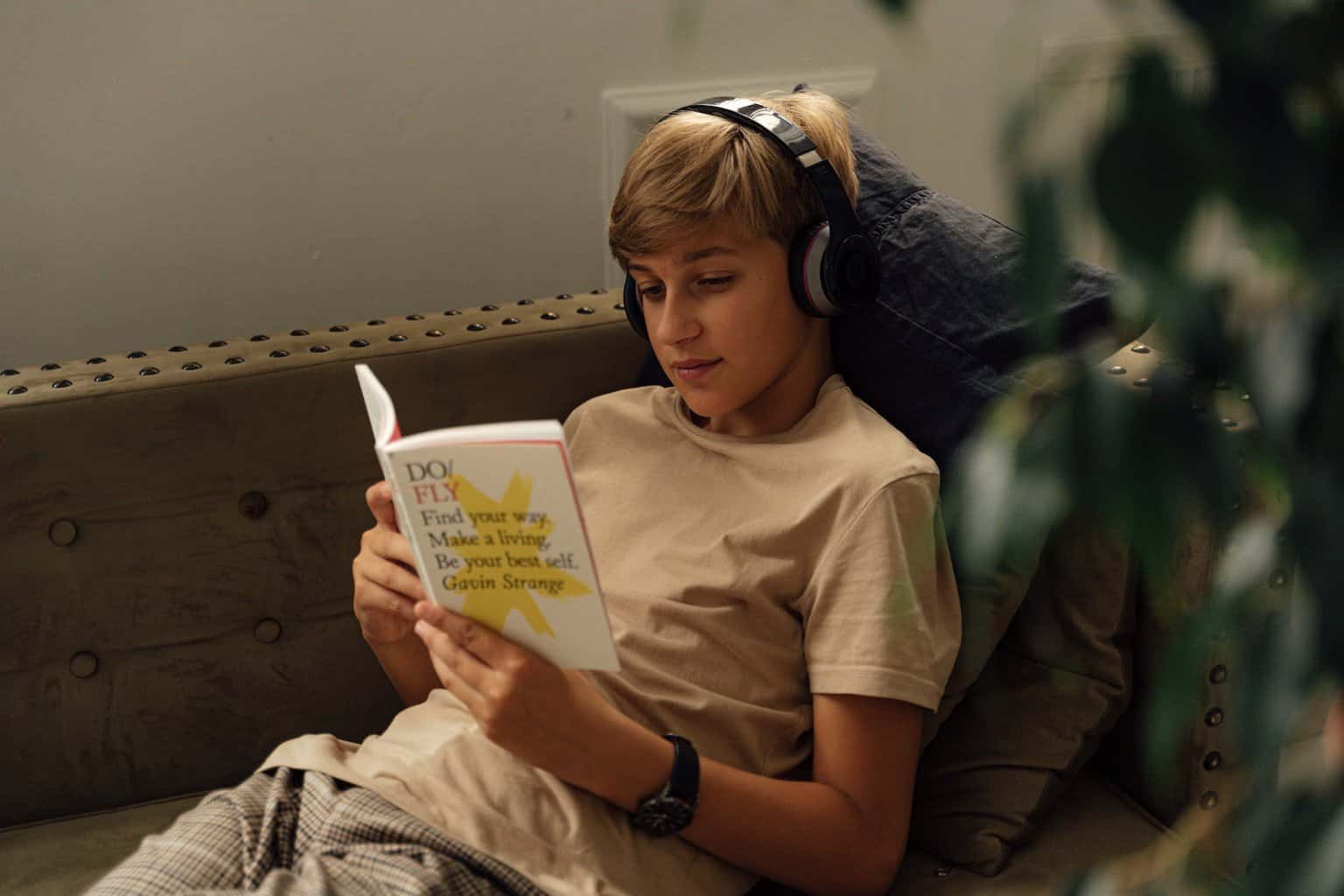 Entertaining Your Older Children - a boy reading a book while listening to music