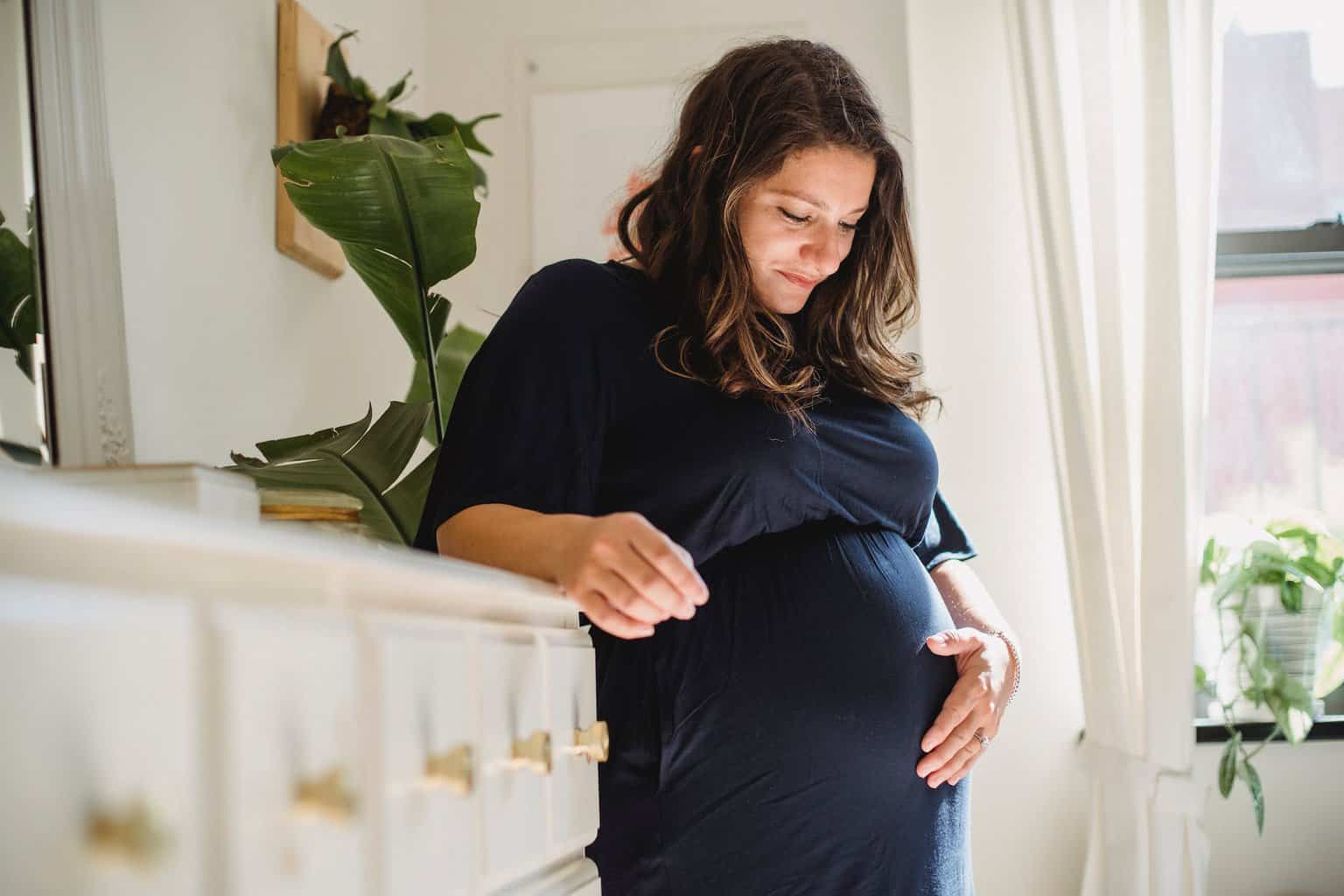 mortgage on maternity leave - smiling pregnant woman caressing tummy in house room